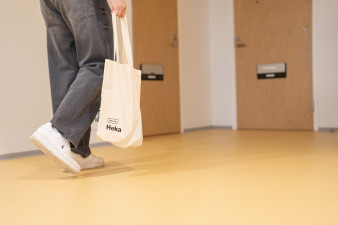 Ihminen kävelee kerrostalon rappukäytävässä, jossa ovia asuntoihin.