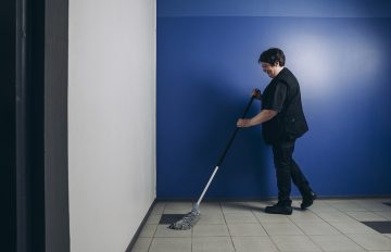 Siivooja pesemässä lattiaa.