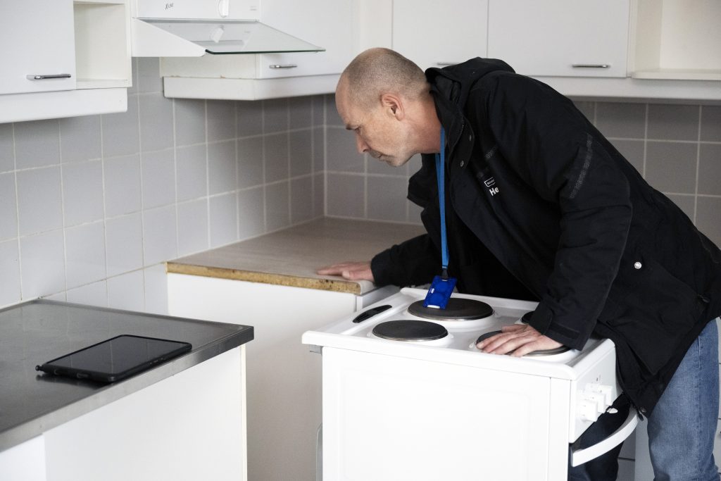 Asunnontarkastaja Markku Pitkänen keittiössä. Hän katsoo uunin taakse.