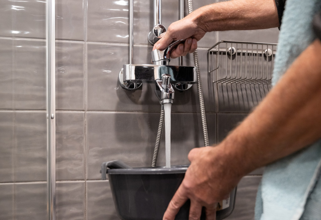 Seinässä olevasta hanasta valutetaan vettä sankoon.