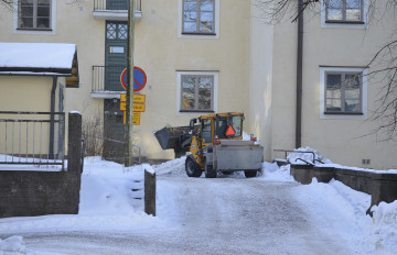 Lumityökone kulkee kerrostalon pihalla.