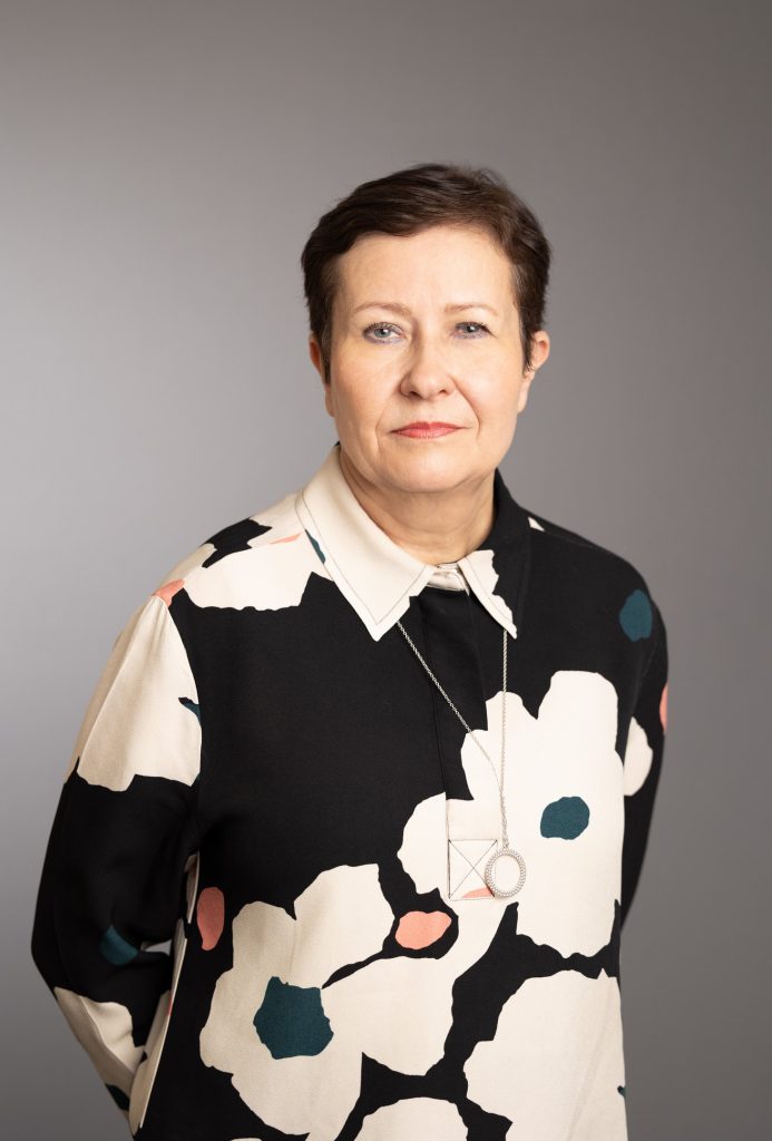 Hekan toimitusjohtaja Jaana Närö vakavana yllään mustavalkoinen, kukkakuvioinen kauluspaita.