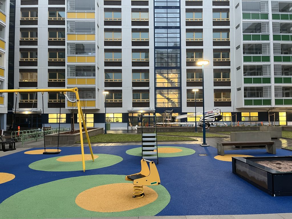 Värikäs leikkipaikka kerrostalon pihalla.