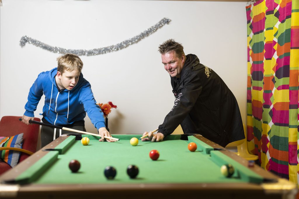 A man and a boy play pool.