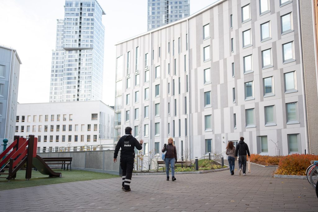 Kiinteistönhoitaja tervehtii asukasta kerrostalon pihalla.