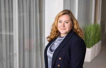 Maria Aspala taustallaan toimistotilaa.