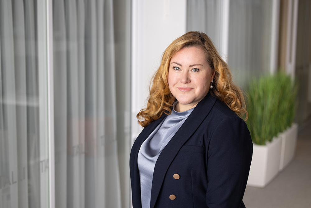 Maria Aspala taustallaan toimistotilaa.