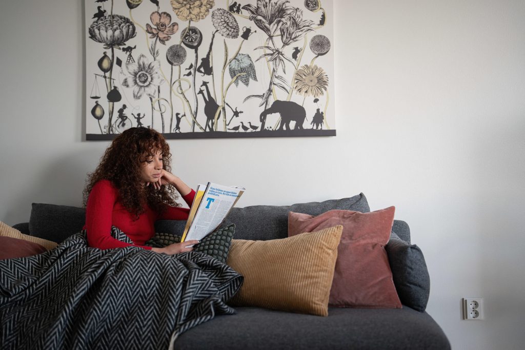 Nainen lukee lehteä sohvalla.