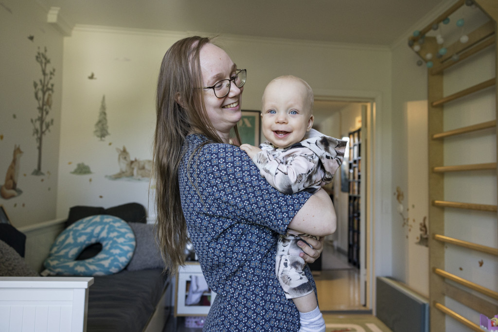 A smiling woman holding a smiling baby.