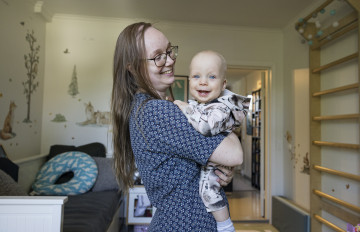 A smiling woman holding a smiling baby.