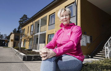 Leena Holmsted istuu Hekan talon edustalla.