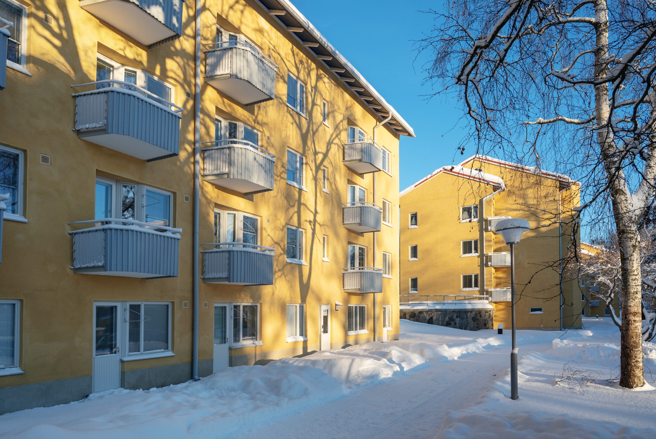 Kaksi keltaista neljäkerroksista taloa ja luminen piha.