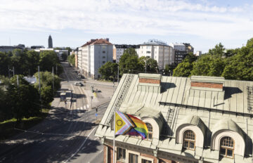 Pride-lippu liehuu Hekan toimiston pihalla. Taustalla näkyy Alppilaa.