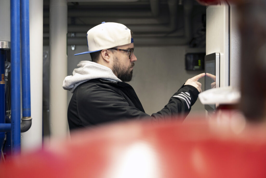 Mika Ringborg tutkii lämmönjakohuoneessa olevaa näyttöä.