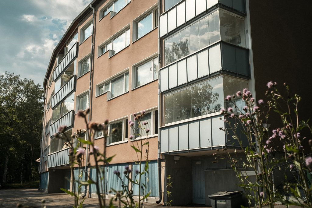 Kerrostalon julkisivua ja parvekkeita ja etualalla kasveja.