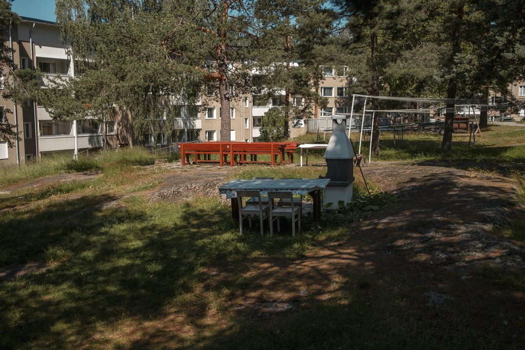 Kallioisella pihalla on pöytäryhmiä ja grilli.