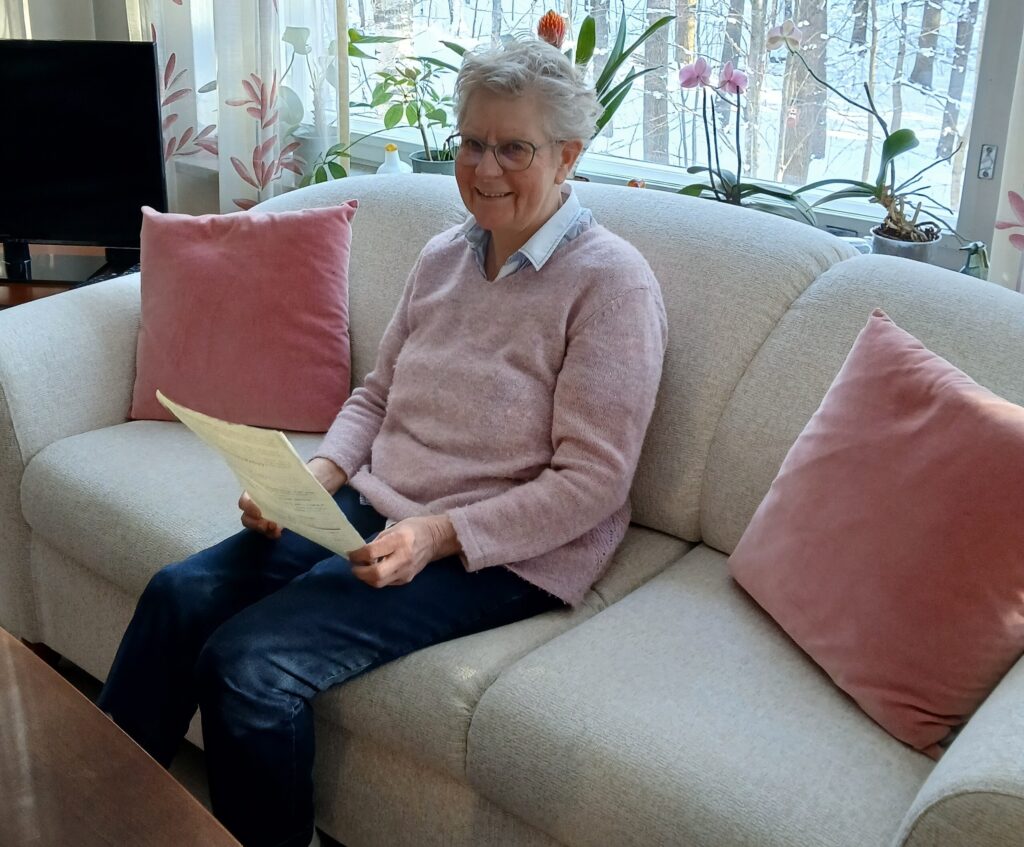 Solveig istuu sohvalla ja pitää kädessään vuokrasopimusta.