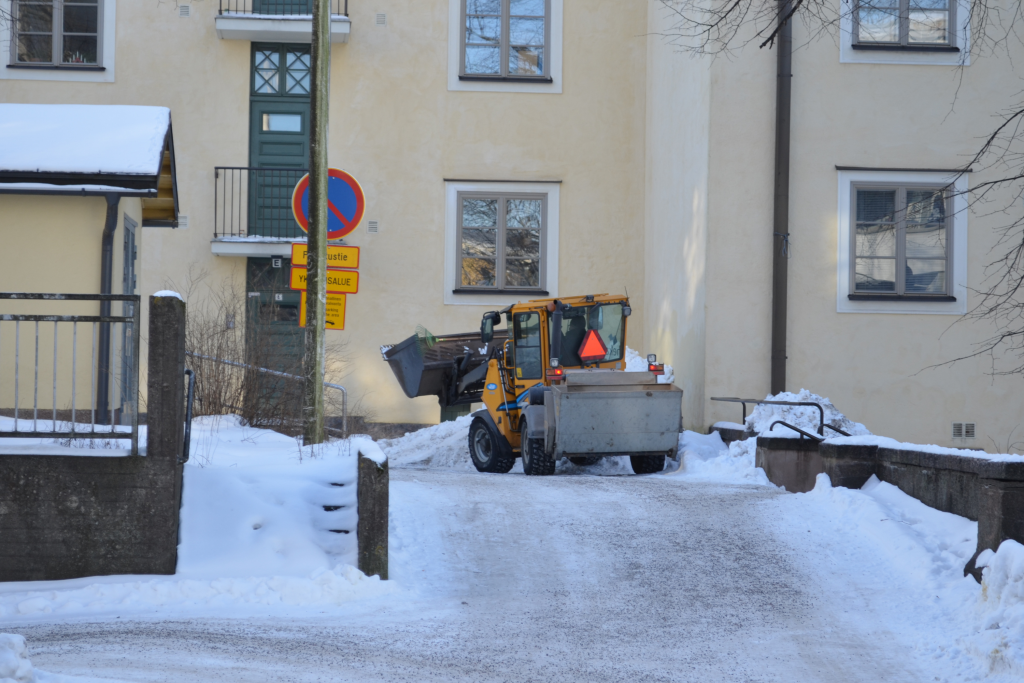 Hekan pienoistraktori tekemässä talvikunnassapitotöitä Heka-talon pihalla.