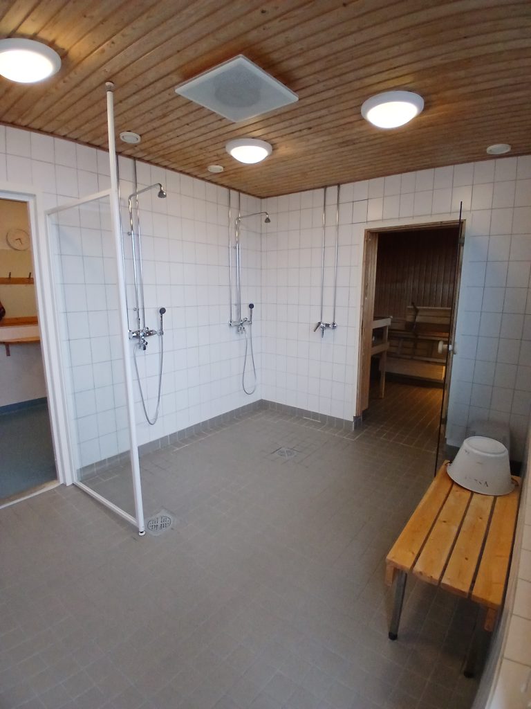 Talosaunan pesuhuone, jossa suihkuja ja penkki.