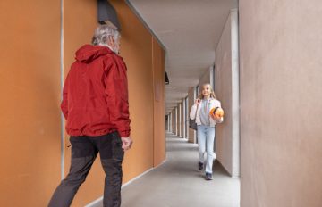 Lapsi ja aikuinen kohtaavat luhtitalon käytävässä.