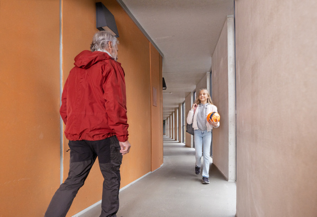 Lapsi ja aikuinen kohtaavat luhtitalon käytävässä.