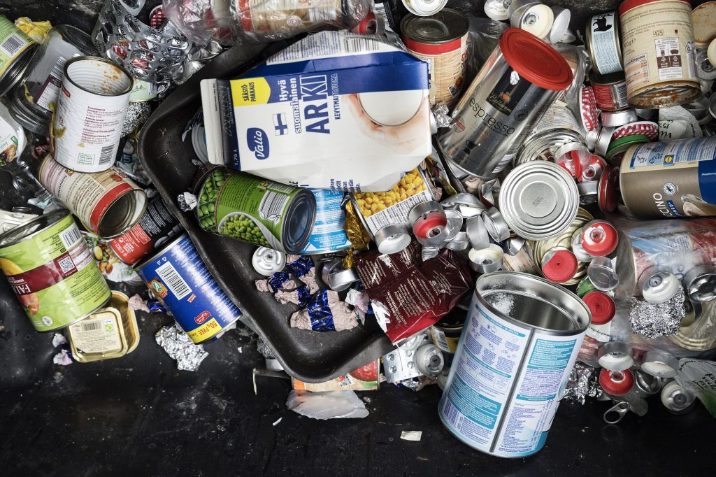 An empty milk carton has been tossed into a metal waste container. 