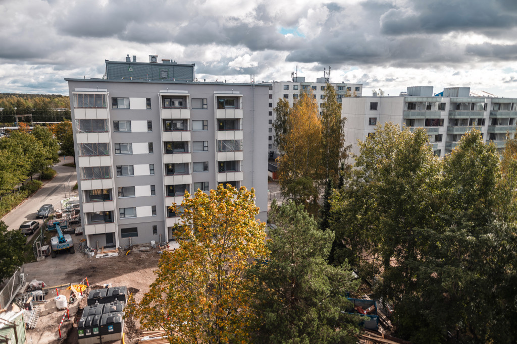 1970-luvun taloja korkealta kuvattuna, pilviä, kellertäviä puita ja hiukan rakennustyömaata. 