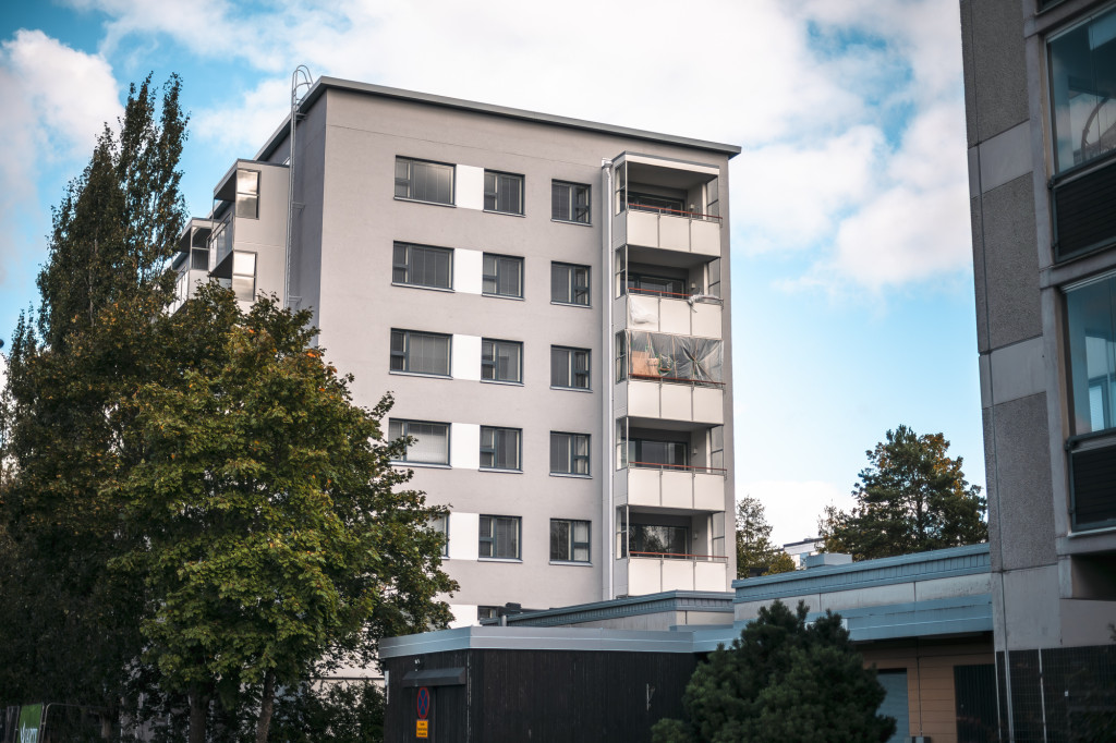 Harmaa talo Tapulikaupungissa ja puita.